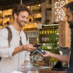 Foreign tourist making a contactless digital payment at an Indian café using a smartphone