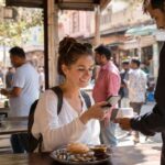 International traveler paying for Indian street food with a smartphone using a QR code at a local food stall, showcasing seamless digital payments in India.
